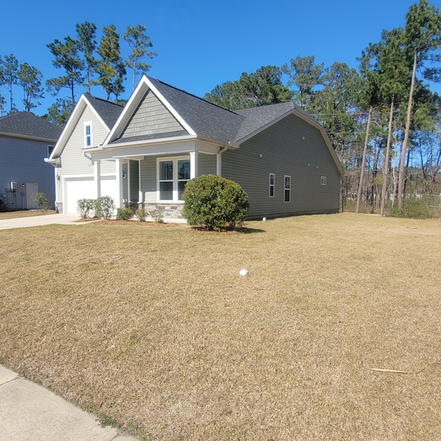 view of front of house with a garage, driveway, a shingled roof, and a front lawn