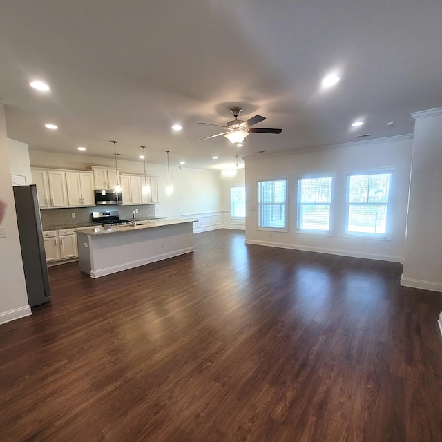 kitchen with dark wood finished floors, appliances with stainless steel finishes, open floor plan, a kitchen island with sink, and ceiling fan