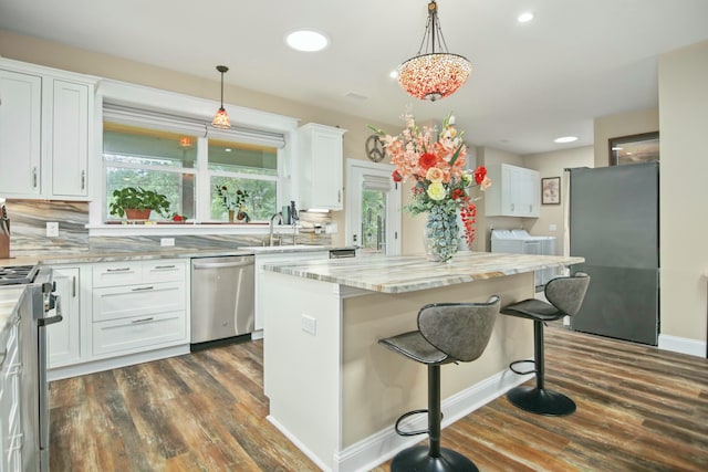 kitchen with white cabinetry, a center island, dark hardwood / wood-style flooring, pendant lighting, and appliances with stainless steel finishes