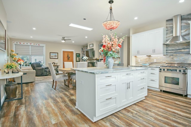 kitchen featuring white cabinets, high end stainless steel range, wall chimney exhaust hood, and light wood-type flooring