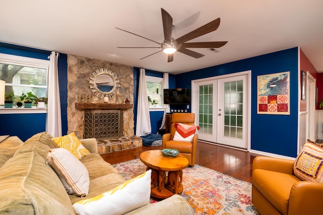 living room featuring a stone fireplace, wood-type flooring, french doors, and ceiling fan