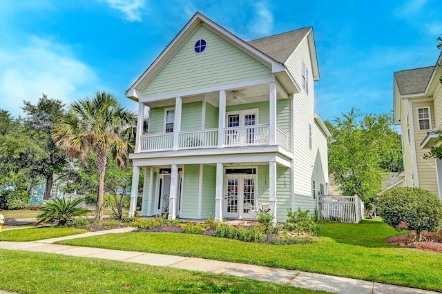 view of front of property featuring french doors, a balcony, a porch, a front lawn, and ceiling fan