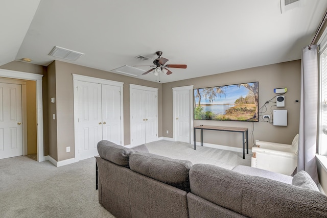 living area featuring light carpet, a ceiling fan, and baseboards