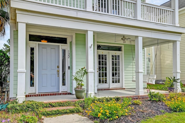 entrance to property featuring a balcony, covered porch, and a ceiling fan