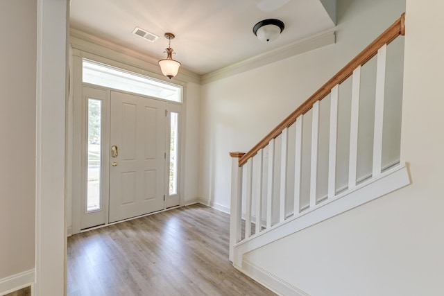 foyer entrance featuring plenty of natural light, stairs, wood finished floors, crown molding, and baseboards