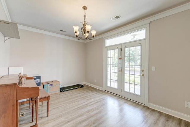 unfurnished office featuring a chandelier, light wood-style flooring, crown molding, and baseboards