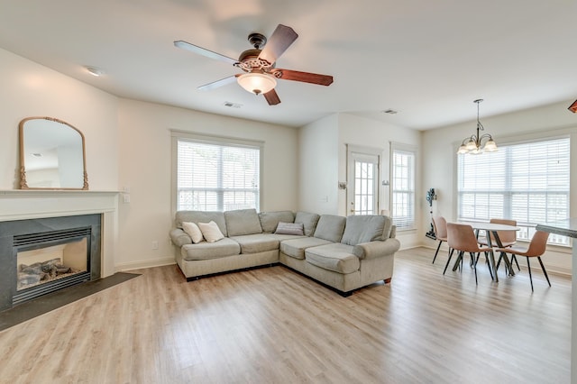 living room with wood finished floors, plenty of natural light, a glass covered fireplace, and ceiling fan