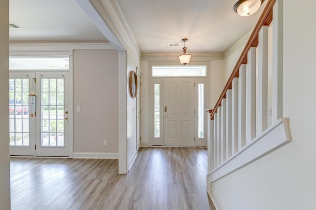 foyer entrance featuring light wood-style floors, stairway, ornamental molding, and baseboards