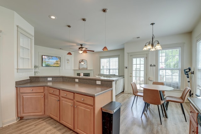 kitchen featuring light wood finished floors, ceiling fan, a chandelier, a peninsula, and decorative light fixtures