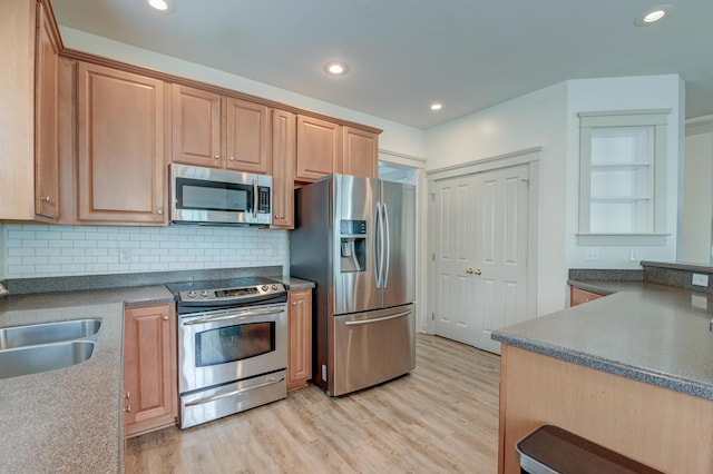 kitchen with stainless steel appliances, tasteful backsplash, light wood finished floors, recessed lighting, and a sink