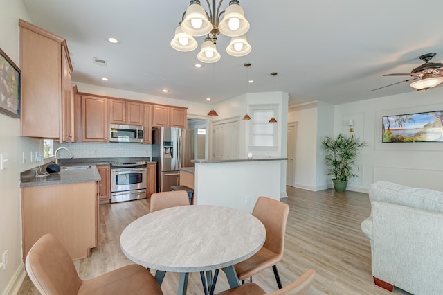 kitchen with stainless steel appliances, a sink, light wood-type flooring, a chandelier, and recessed lighting