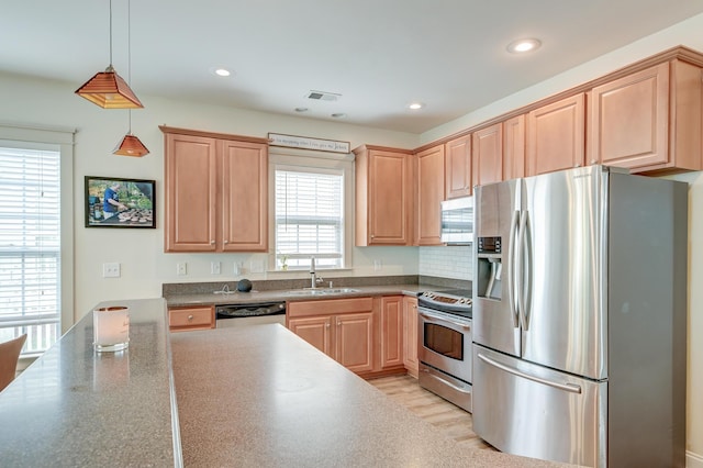 kitchen featuring appliances with stainless steel finishes, a sink, light brown cabinets, decorative light fixtures, and recessed lighting