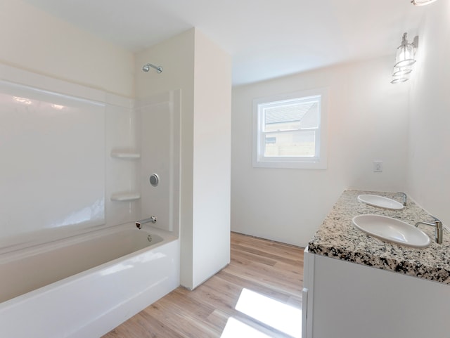 bathroom featuring wood-type flooring, washtub / shower combination, and vanity