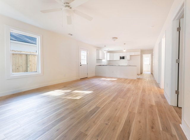 unfurnished living room featuring ceiling fan and light hardwood / wood-style floors