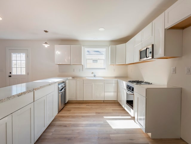 kitchen with light hardwood / wood-style flooring, white cabinetry, appliances with stainless steel finishes, and decorative light fixtures