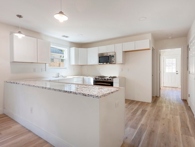 kitchen with stainless steel appliances, white cabinetry, kitchen peninsula, and hanging light fixtures