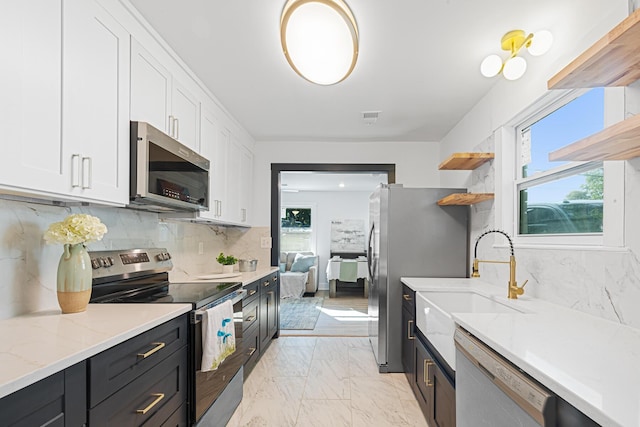 1129 Dickson Ave, Hanahan, SC 29410 - kitchen featuring appliances with stainless steel finishes, white cabinets, light marble finish flooring, and backsplash