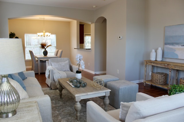 living room with a wealth of natural light, dark wood-type flooring, and a chandelier