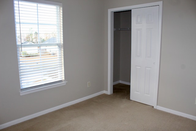 unfurnished bedroom featuring light colored carpet and a closet