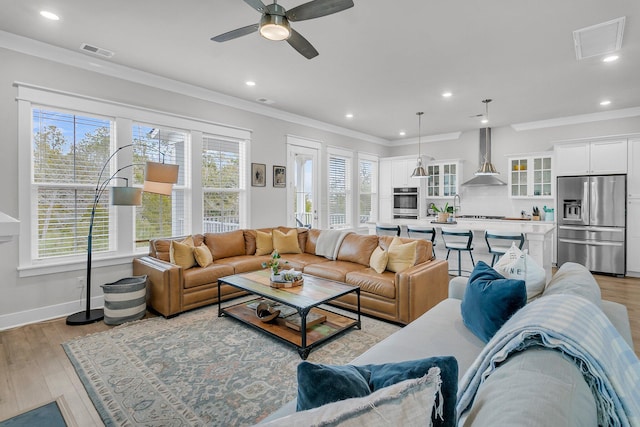 living room with crown molding, plenty of natural light, and light hardwood / wood-style floors