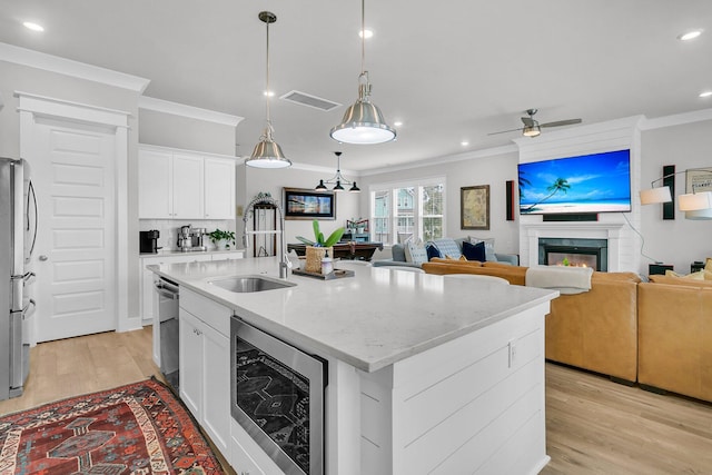 kitchen with a center island with sink, ceiling fan, white cabinetry, stainless steel appliances, and beverage cooler