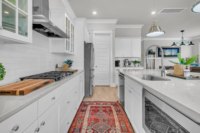 kitchen featuring decorative backsplash, white cabinetry, hanging light fixtures, and wall chimney range hood