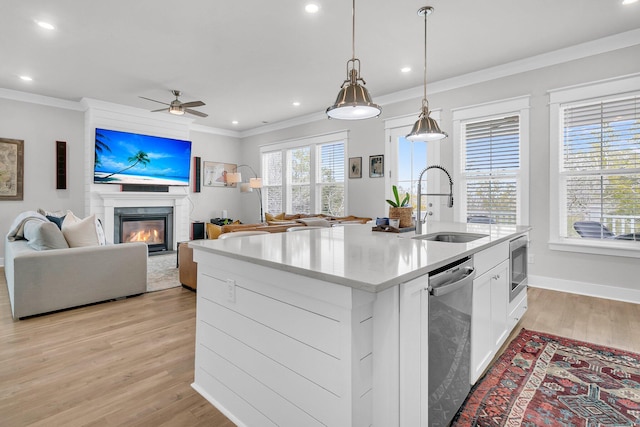 kitchen with a kitchen island with sink, white cabinets, sink, light wood-type flooring, and stainless steel appliances