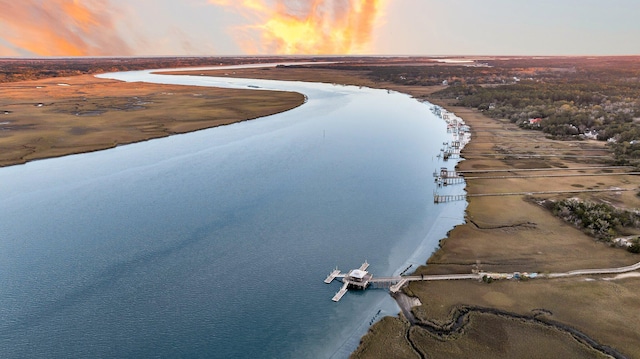 aerial view at dusk with a water view and a beach view