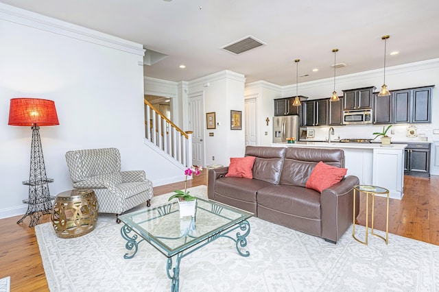 living area with visible vents, baseboards, light wood finished floors, recessed lighting, and stairs