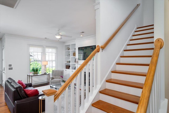 stairs with ornamental molding, visible vents, a ceiling fan, and wood finished floors