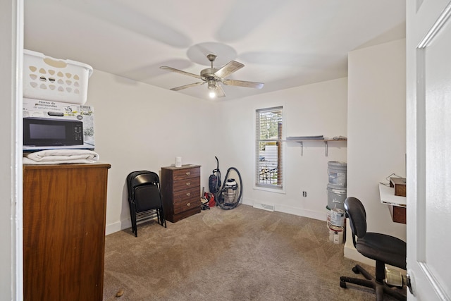 office area with carpet flooring, a ceiling fan, visible vents, and baseboards