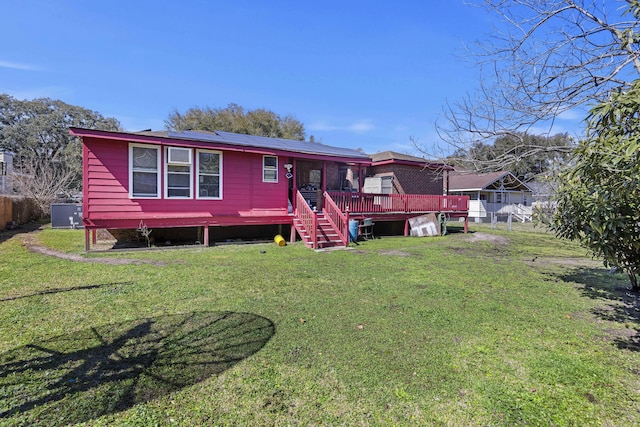 view of front of property with a deck, a front yard, a fenced backyard, and roof mounted solar panels