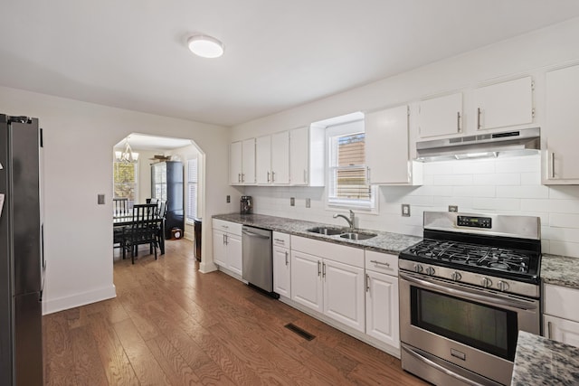 kitchen featuring visible vents, arched walkways, a sink, appliances with stainless steel finishes, and under cabinet range hood