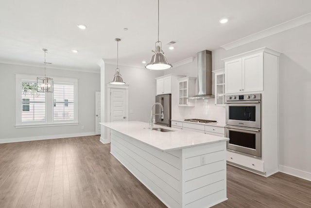 kitchen with stainless steel appliances, a sink, wall chimney range hood, decorative backsplash, and crown molding