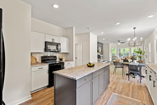 5950 Kelseys Mill Rd, Ravenel, SC 29470 - kitchen featuring light wood-style floors, white cabinets, black appliances, a kitchen island, and decorative backsplash