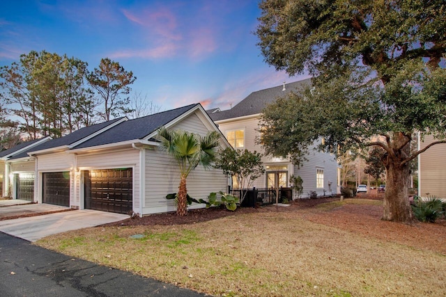 property exterior at dusk with a garage and a yard