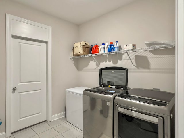 clothes washing area with light tile patterned floors and washer and dryer