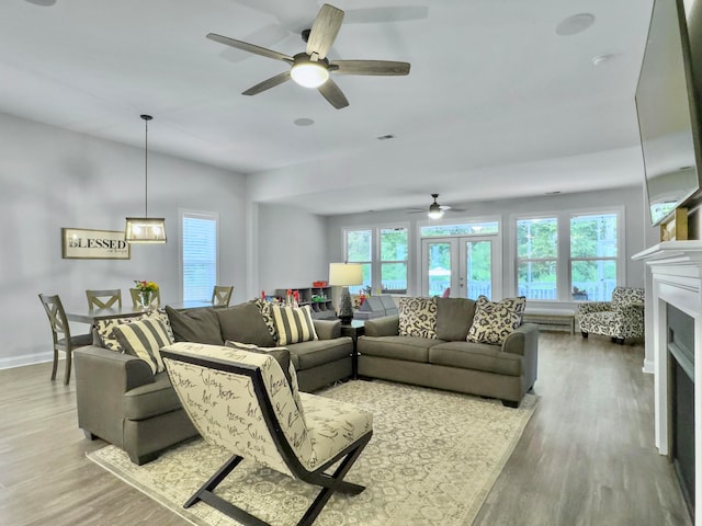 living room featuring ceiling fan, french doors, hardwood / wood-style floors, and a healthy amount of sunlight