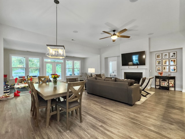 dining space with ceiling fan with notable chandelier, hardwood / wood-style flooring, and french doors