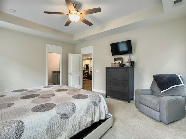 carpeted bedroom featuring ceiling fan, a raised ceiling, and ensuite bathroom