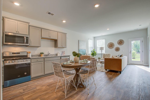 kitchen featuring stainless steel appliances, visible vents, gray cabinetry, a sink, and wood finished floors