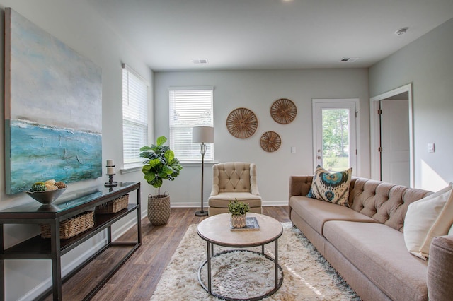 living area with dark wood-type flooring, visible vents, and baseboards