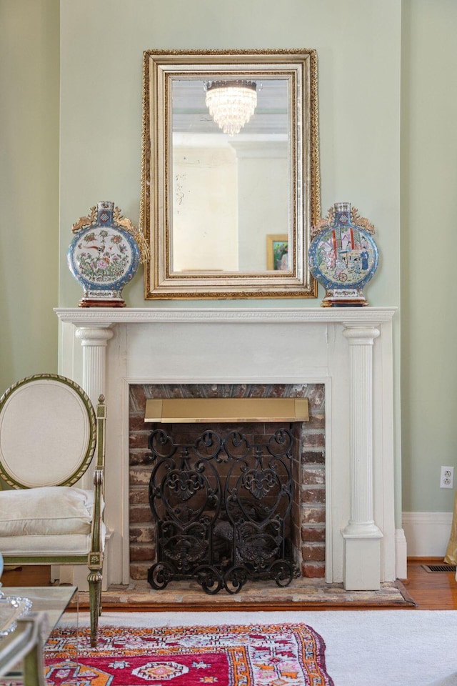 interior details with a fireplace, visible vents, a chandelier, and wood finished floors
