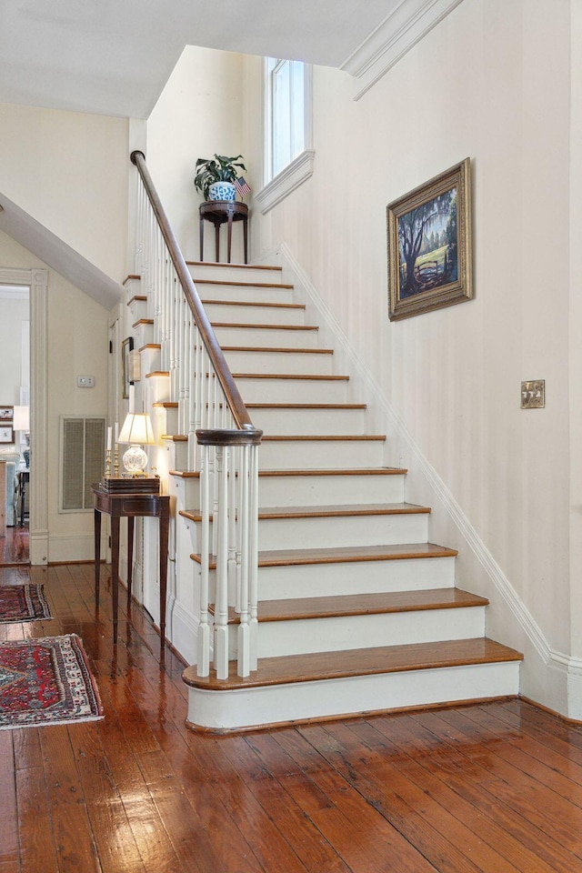 stairway featuring visible vents, baseboards, and hardwood / wood-style flooring
