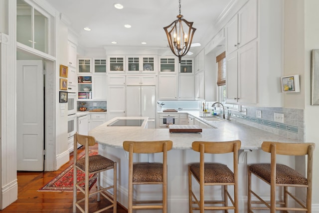 kitchen featuring a peninsula, white cabinetry, and black electric stovetop