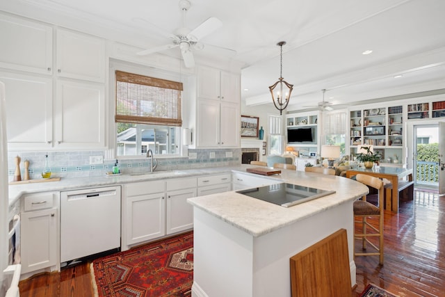 kitchen featuring ceiling fan with notable chandelier, a sink, decorative backsplash, black electric stovetop, and white dishwasher