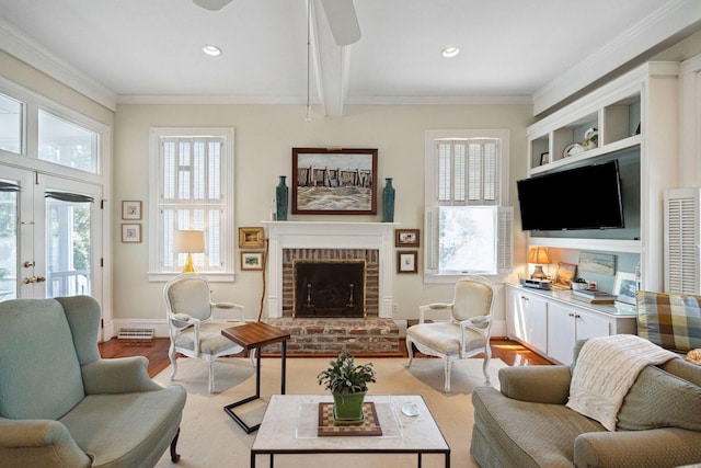 living area featuring a fireplace, ornamental molding, light wood-style flooring, and a ceiling fan