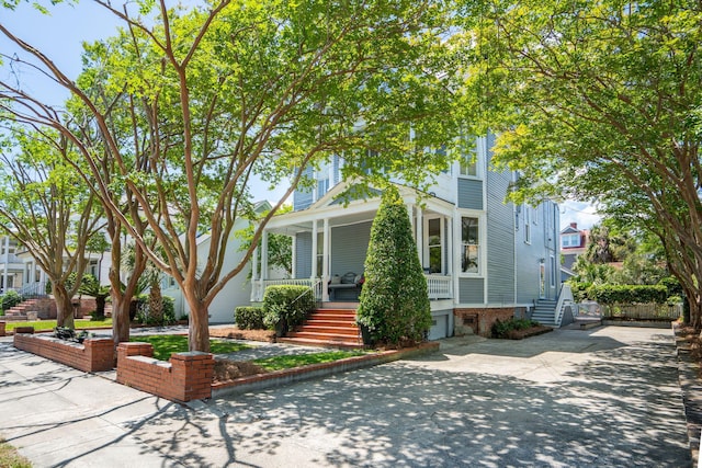 view of front of property featuring concrete driveway, stairway, and covered porch