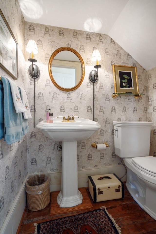 half bath with lofted ceiling, toilet, and wood finished floors