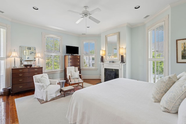 bedroom featuring wood finished floors, visible vents, a fireplace, crown molding, and baseboards